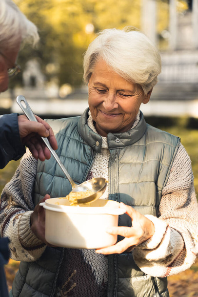 Elderly Caucasian woman getting food from a man nature background senior people wellbeing support concept medium shot selective focus  - Photo, image
