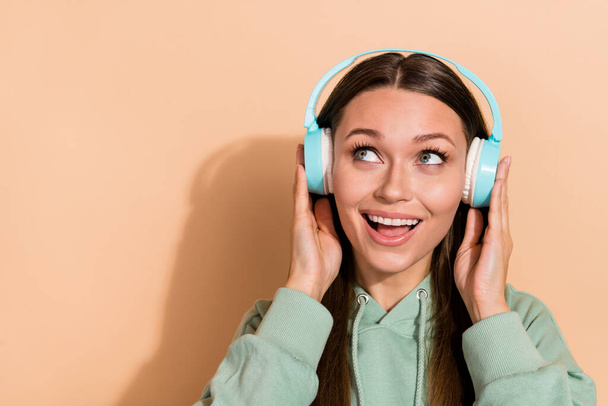Portrait of attractive cheerful dreamy brown-haired girl listening single stereo copy space isolated over beige pastel color background - Zdjęcie, obraz