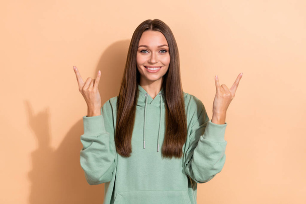 Portrait of attractive cheerful girl having fun showing double horn sign isolated over beige pastel color background - 写真・画像