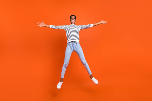 Full length body size view of attractive cheerful girl jumping having fun isolated over vivid orange color background - Foto, Bild
