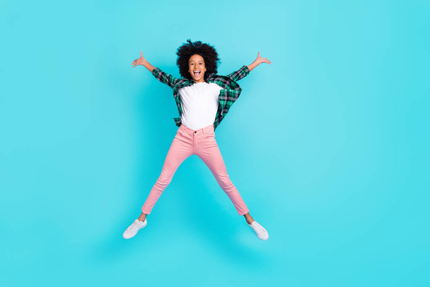 Фото веселой сумасшедшей активной леди прыжок поднять руки весело носить клетчатую рубашку изолированный бирюзовый фон - Фото, изображение