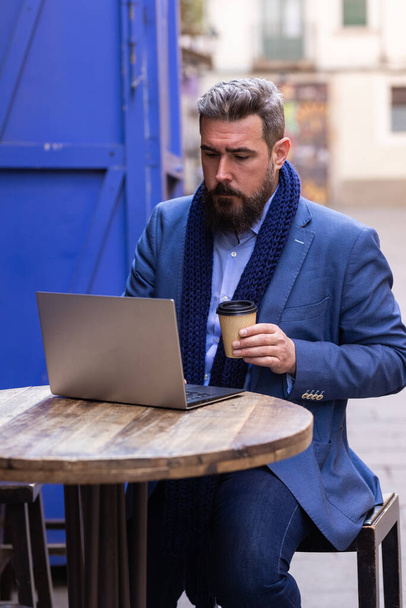 Felnőtt férfi kávézó kívül használja a laptopját - Fotó, kép