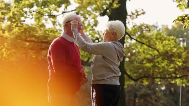 Elderly Caucasian woman putting glasses on her husband people suffering from bad eyesight support concept selective focus copy space medium shot  - Footage, Video