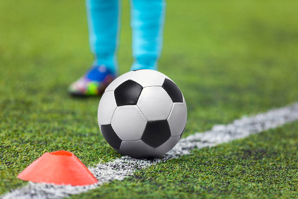 サッカーの足はサイドラインのサッカーボールに向かって走っています。ピッチサイドライン上に横たわる古典的なサッカーボール - 写真・画像
