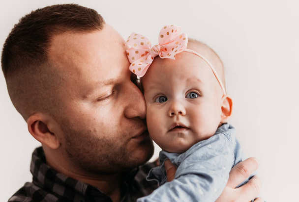 young father raising his cute baby girl and looking at her at home. Happiness of being father and parenthood, lovely warm moment of dad and baby, lifestyle concept - Фото, зображення