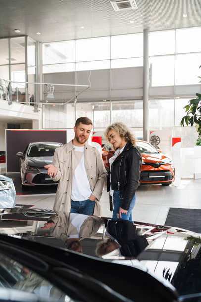 Beautiful young couple in a car dealership choose a car - Valokuva, kuva