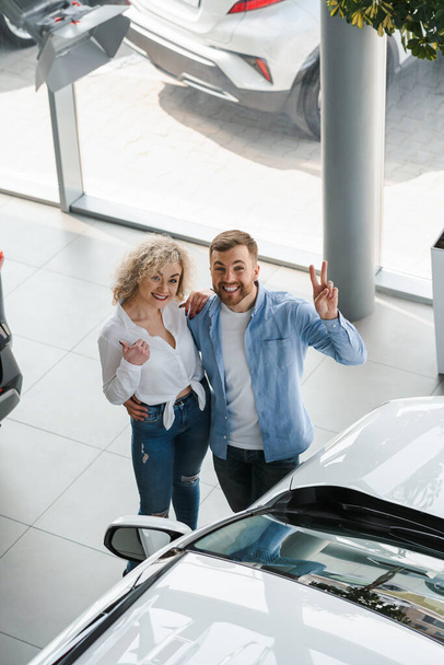 Satisfied young couple in a car dealership - Fotografie, Obrázek