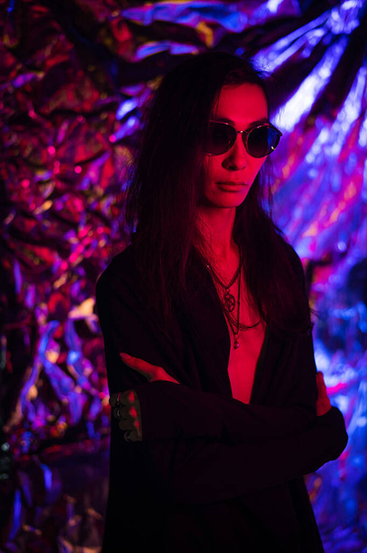 Portrait of a transgender model in sunglasses in a studio with neon lighting. - Foto, imagen