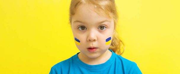 Uma menina com uma bandeira ucraniana pintada de amarelo e azul em suas bochechas. - Foto, Imagem