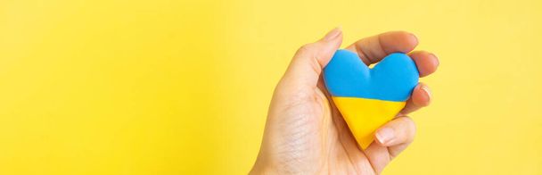 Yellow and blue heart in the colors of the flag of Ukraine in the hand of a woman. - Фото, зображення