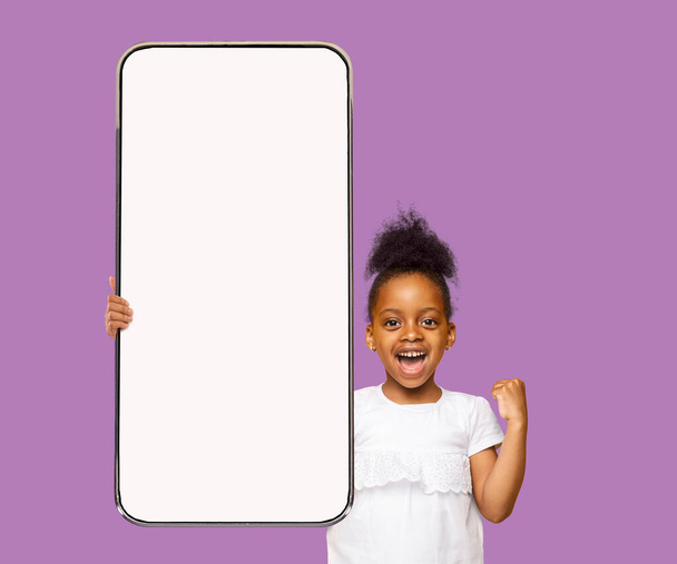 Linda niña negra preescolar que muestra el teléfono inteligente, maqueta - Foto, imagen