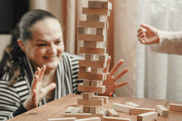 Mom and daughter play a board game, build a tower from wooden blocks. - Photo, Image