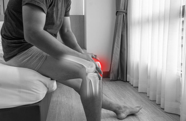 Close up Knee and Leg Pain in a man, the Young man holding his knee in pain inflammation symptoms sitting on the bed medical healthcare concept - Foto, imagen