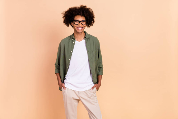 Photo of satisfied glad young man hands pockets toothy smile look camera isolated on beige color background - Foto, Bild