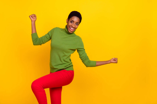 Photo of sweet lucky trans woman wear green turtleneck dancing rising fists empty space isolated yellow color background - Фото, зображення