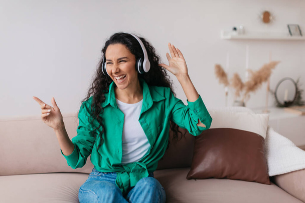 Ευτυχισμένη κυρία φορώντας ακουστικά ακούγοντας μουσική διασκεδάζοντας εσωτερικά - Φωτογραφία, εικόνα