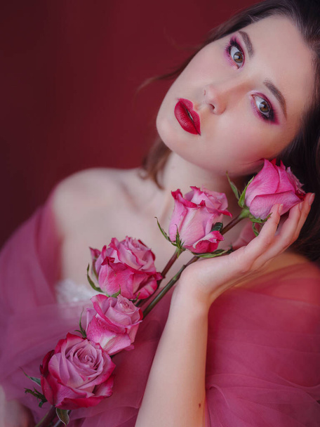 Ελκυστική μελαχρινή Ασιάτισσα με όμορφο μπουκέτο λουλούδια. Όμορφη γυναίκα με λαμπερό μακιγιάζ. Πορτραίτο τέχνης με τριαντάφυλλα. Έννοια της φροντίδας των νέων και του δέρματος - Φωτογραφία, εικόνα