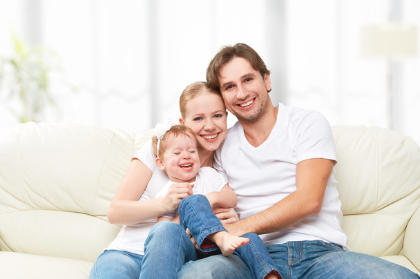 Ευτυχισμένη οικογένεια μητέρα, πατέρας, κόρη μωρό παιδί στο σπίτι στον καναπέ παίζοντας και γελώντας - Φωτογραφία, εικόνα