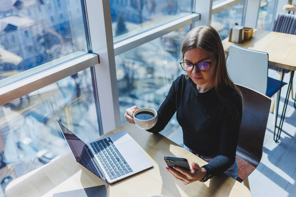Счастливая европейская женщина работает онлайн в кафе, используя ноутбук и кофейное пространство. Успешная женщина-фрилансер, печатающая на ноутбуке, удаленная работа - Фото, изображение
