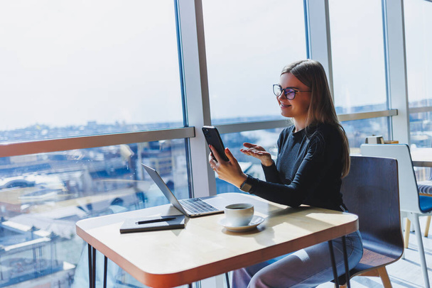 Szczęśliwa Europejka pracująca online w stołówce przy użyciu laptopa i miejsca do kopiowania kawy. Sukces kobiet freelancer wpisując na laptopie, zdalnej pracy - Zdjęcie, obraz