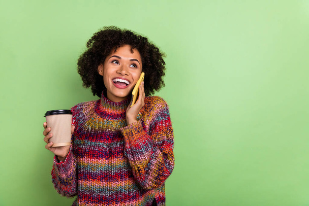 Portrait of attractive cheerful girl hold coffee speak telephone isolated on green color background - 写真・画像