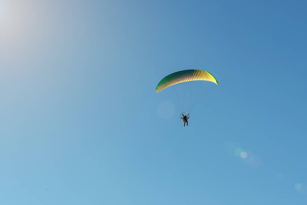 Motorized paraglider flies in the blue sky, extreme sports. - Photo, image