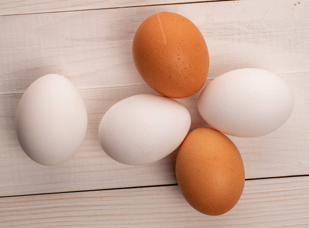 Unos huevos de pollo orgánicos frescos deliciosos, beige y blanco, en una encimera de madera blanca, vista superior. - Foto, Imagen