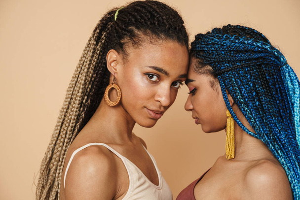 Fiatal fekete két nő afro copfos pózol fej-fej mellett elszigetelt bézs háttér - Fotó, kép
