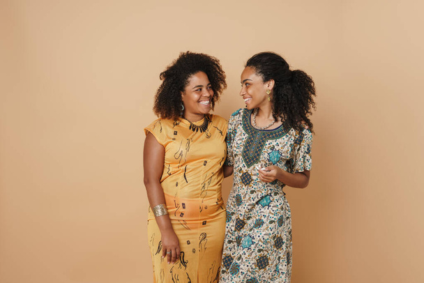 Young black two women hugging and smiling at camera isolated over beige background - Zdjęcie, obraz