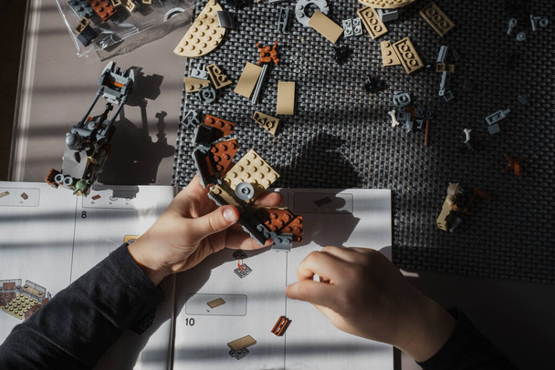 21.03.2022. Batumi, Georgia. Boy child manually folds Lego constructor at the table. Top view. Star Wars. Disney - Foto, Imagem