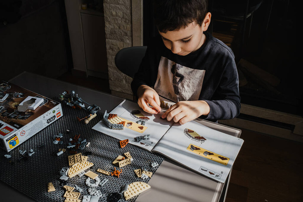 21.03.2022. Batumi, Georgia. Niño niño pliega manualmente Lego constructor en la mesa.. Star Wars. Disney. - Foto, Imagen