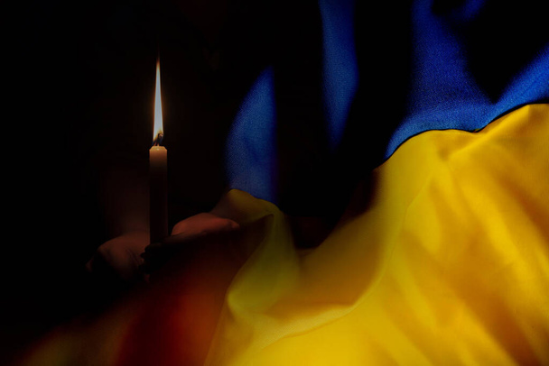La bandera nacional de Ucrania es de color amarillo y azul sobre el fondo de una vela, lloramos a los que murieron en la guerra en Ucrania 2022 - Foto, imagen