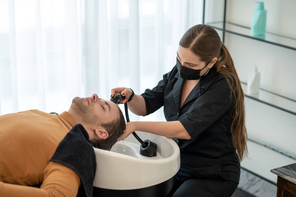 Female hairdresser washing hair to the customer - Valokuva, kuva