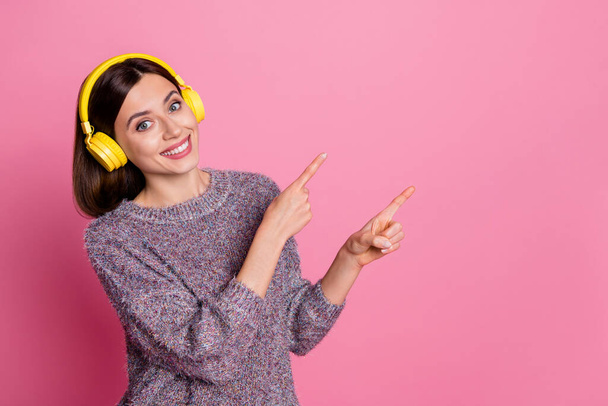 Photo of shiny charming lady dressed sweater earphones pointing empty space isolated pink color background - Φωτογραφία, εικόνα