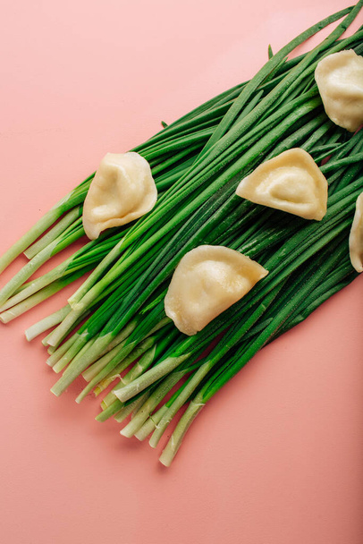 green fresh chives on a pink background. dumpling laid out on top. High quality photo - Фото, изображение