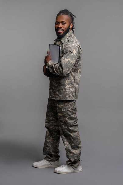 Young soldier pressing documents to his chest - Foto, imagen