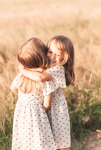 Két kis boldog ikerlány játszik együtt a természetben nyáron. Lány barátság és ifjúsági koncepció. Aktív gyermekéletmód. - Fotó, kép