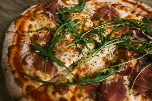 Delicious hot meat pizza with prosciutto and salami on a wooden table. - Valokuva, kuva