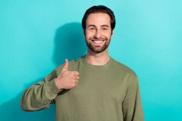 Photo of nice brunet millennial guy thumb up wear green pullover isolated on teal color background - Foto, Bild