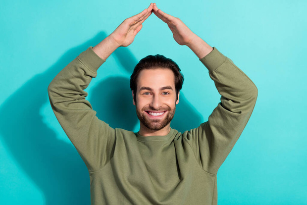 Photo of nice brunet millennial guy hands roof wear green shirt isolated on teal color background - Fotoğraf, Görsel