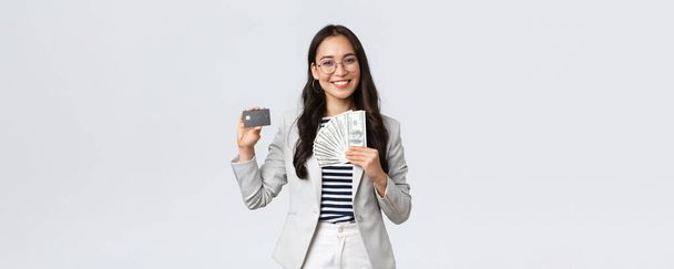 İş, finans ve istihdam, girişimci ve para kavramı. Başarılı Asyalı iş kadını, gelirin, kredi kartının ve paranın nasıl arttığını gösteriyor, gülümseyen kamera - Fotoğraf, Görsel