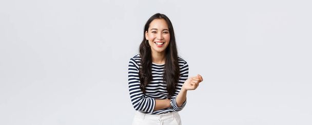 Lifestyle, people emotions and casual concept. Carefree happy outgoing asian woman having fun talking to people, laughing and smiling upbeat, standing white background cheerful - Φωτογραφία, εικόνα