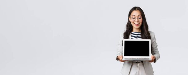 Business, finance and employment, female successful entrepreneurs concept. Enthusiastic businesswoman in suit and glasses showing presentation, demonstrate her project on laptop screen - Foto, imagen