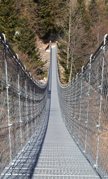 頑丈な鋼ケーブルで作られたチベット橋と呼ばれる長いつり橋は、人々なしで2つの山の尾根を接続します - 写真・画像