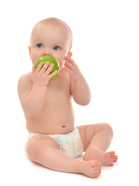 Happy child baby boy sitting in diaper and eating green apple - Foto, Imagem