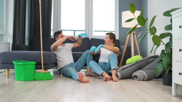 La coppia stanca si siede sul pavimento in una stanza e si dà cinque a vicenda dopo aver finito di pulire la casa. Rallentatore - Filmati, video