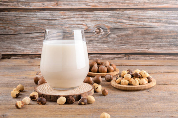 Веганське не-щоденне лісове молоко в склянці з цілими лісовими горіхами на лляній серветці на сільському дерев'яному фоні. Безлактозовий напій з лісових горіхів - це альтернативне молоко на основі рослин. Здоровий молочний продукт, крупним планом
 - Фото, зображення