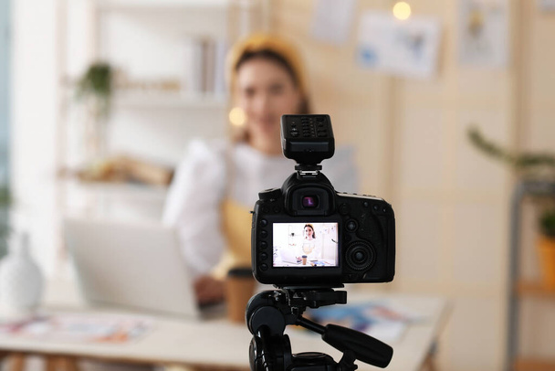 Young female clothes stylist recording video in studio, view on screen of modern video camera - Фото, изображение