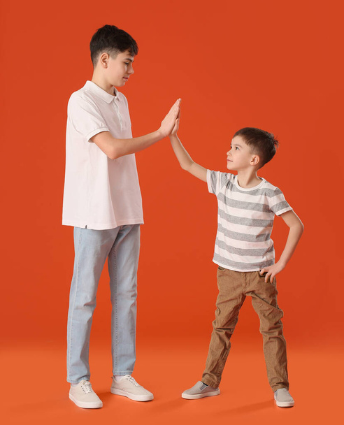 Portrait of cute brothers giving high-five to each other on color background - Photo, Image