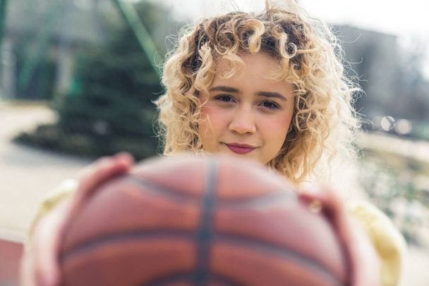 Pretty young Caucasian woman holding a basketball ball in front of her closeup copy space  - Фото, зображення